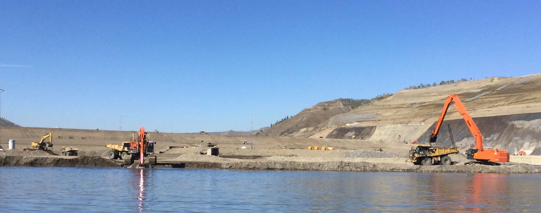 Excavators and trucks working on dam