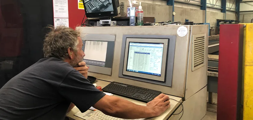 A man looks at a computer screen in a factory setting.