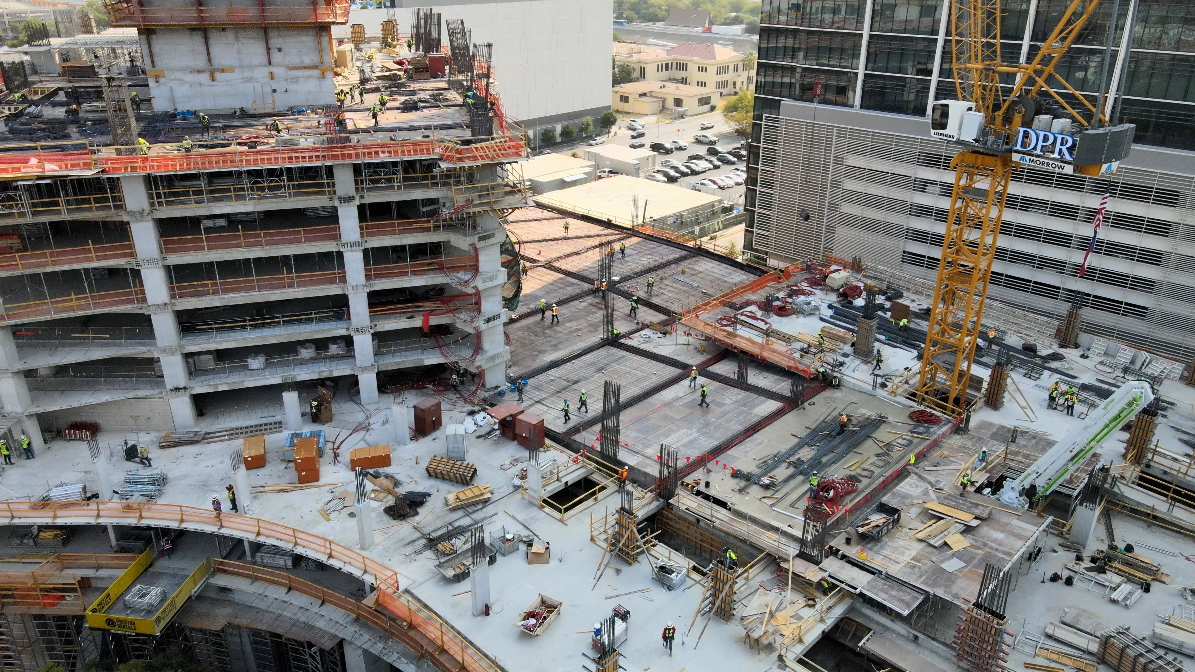 Aerial view of a large construction site with a crane and multiple workers.