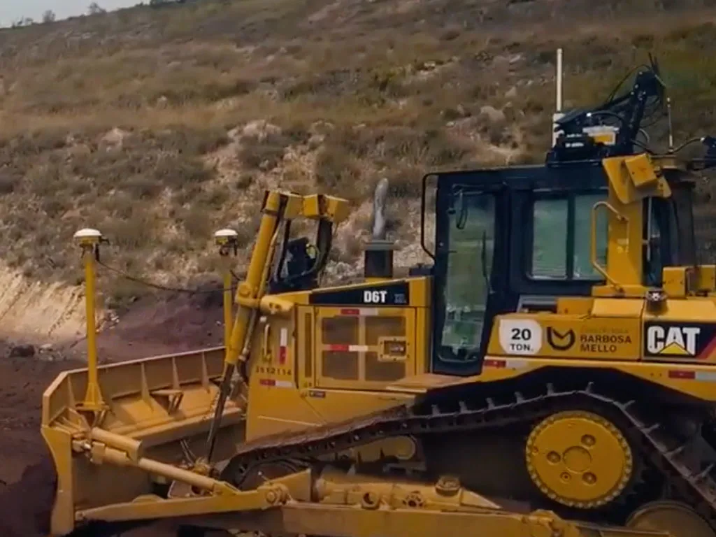 A yellow Caterpillar D6T dozer is working on a construction site, with a dirt embankment in the background.