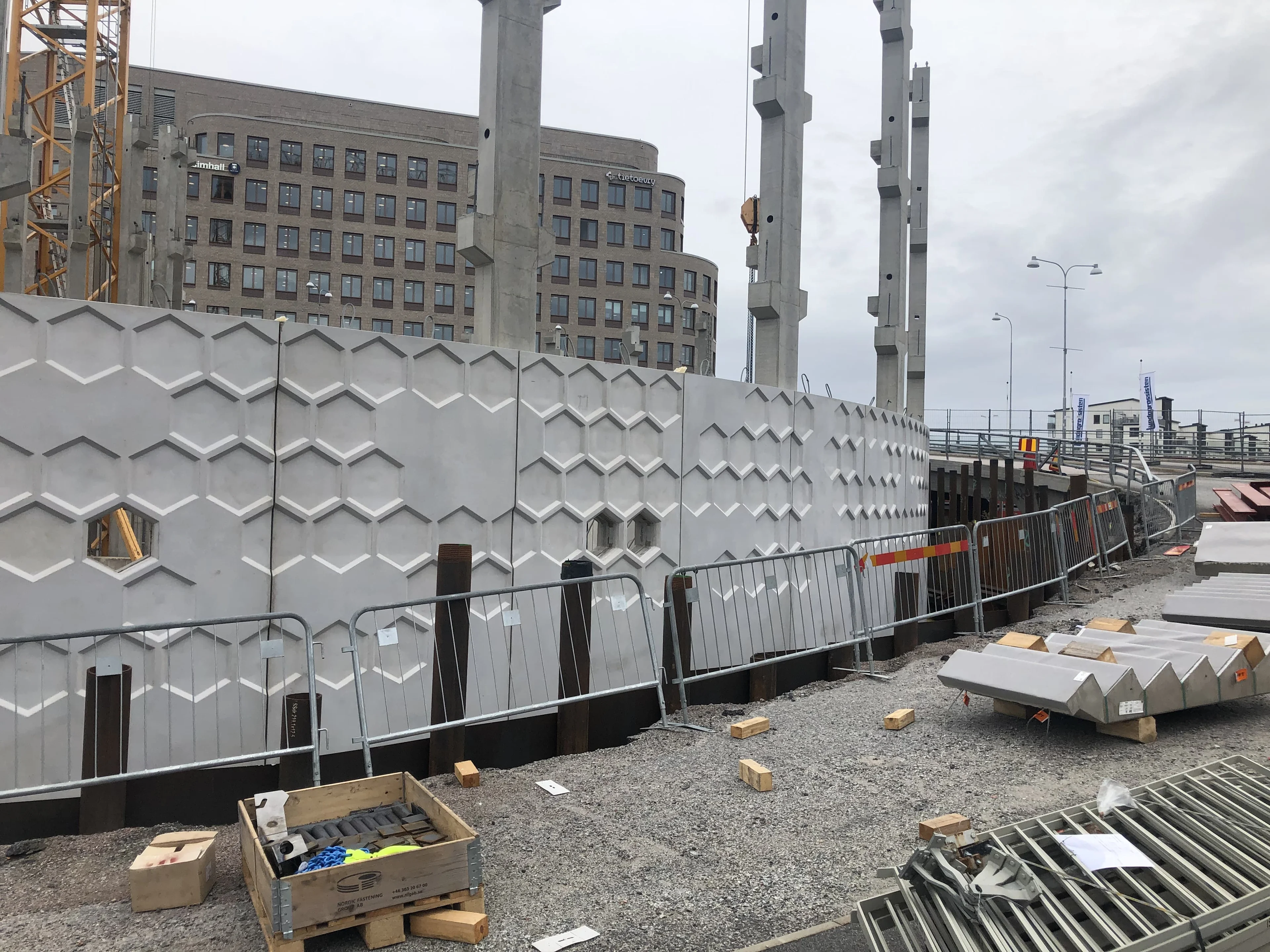 A concrete wall with a geometric honeycomb pattern is under construction.