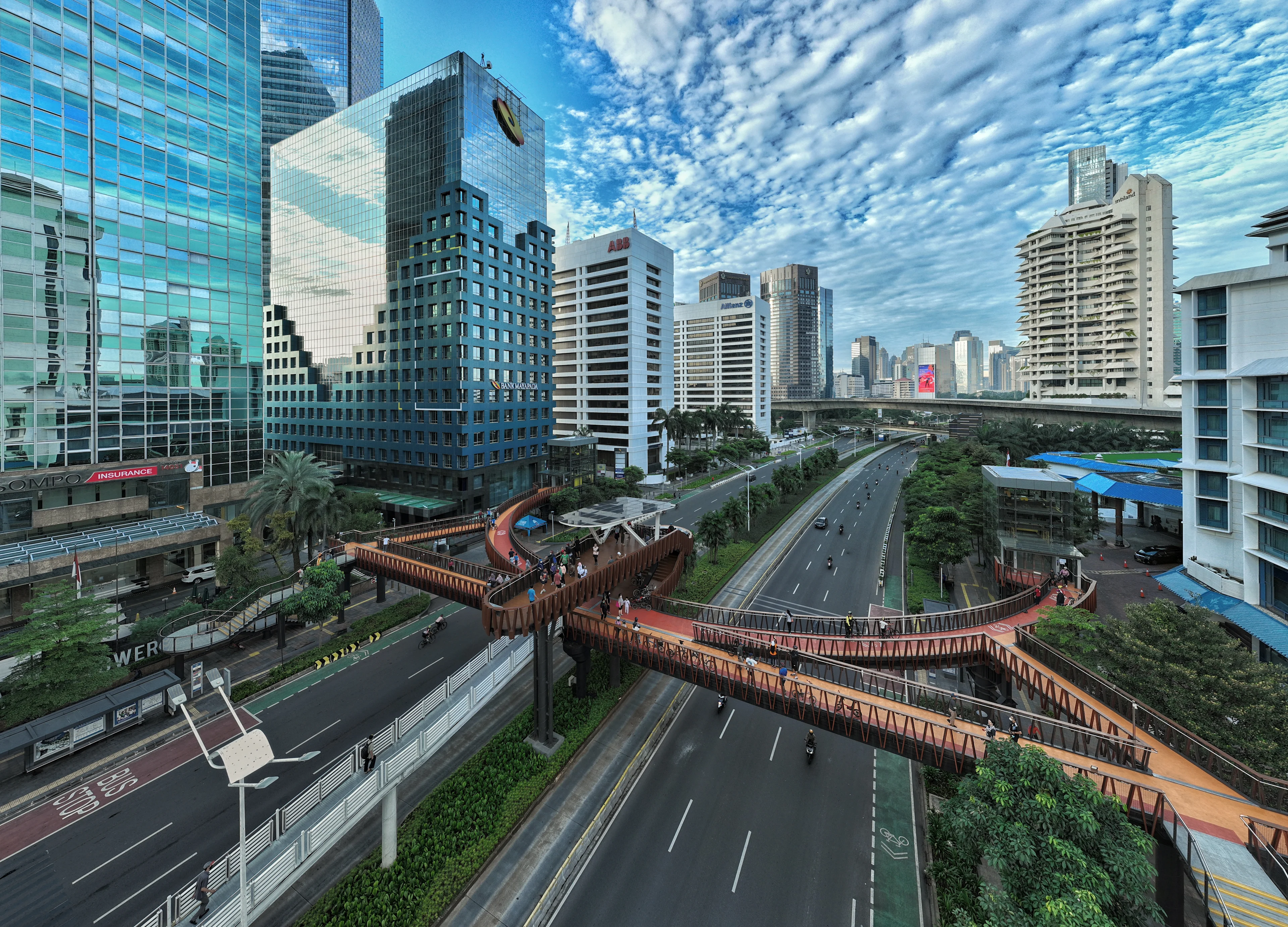 The Pinisi Crossing Bridge in the daytime, with pedestrians on the bridge and traffic below.