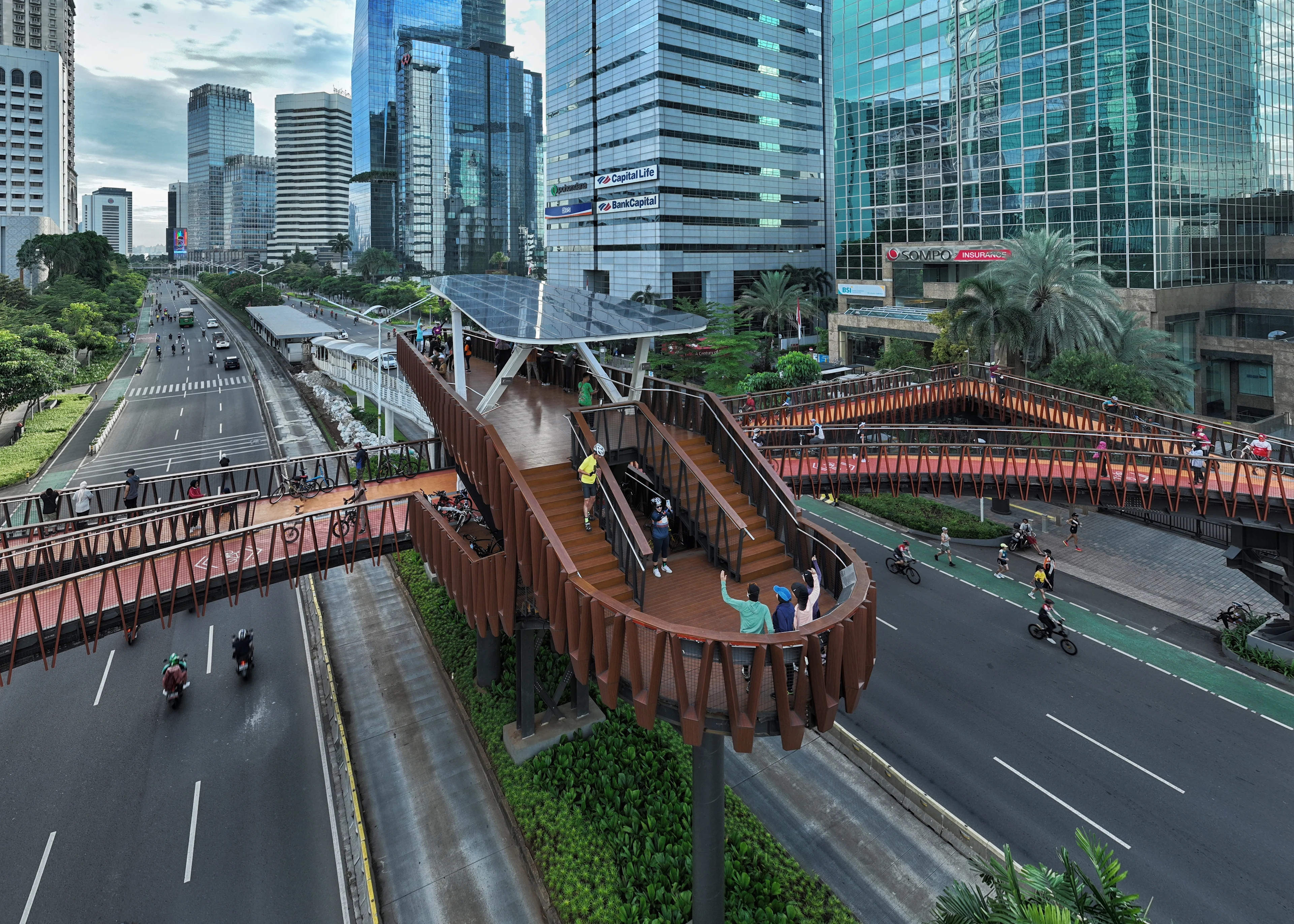 The Pinisi Crossing Bridge in daylight above the city traffic and high-rise buildings in the background.
