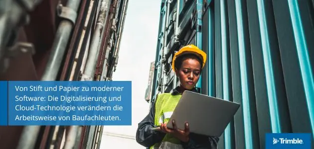 Construction worker in hard hat and vest uses laptop near shipping containers.