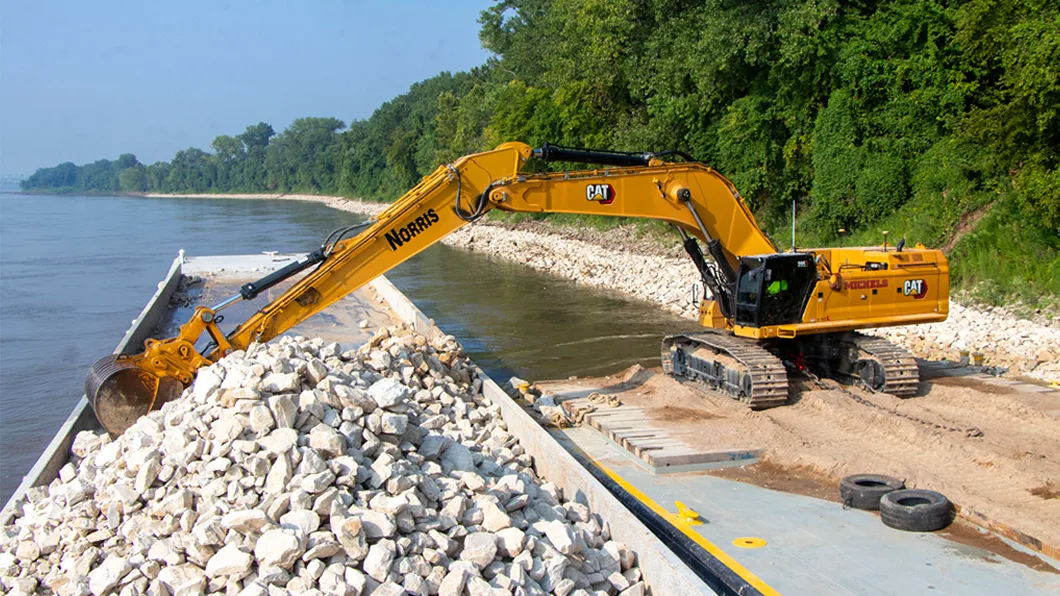 An excavator placing rock along the shoreline