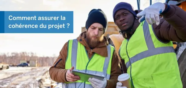 Two construction workers in high-visibility vests look at a tablet.