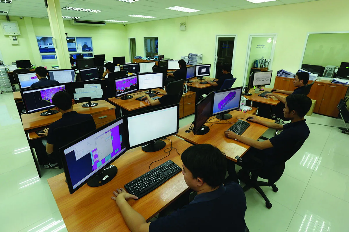 A group of employees sit at their desks, working on computers in an office environment.