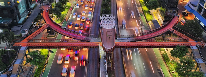 The Pinisi Bridge at night above ongoing traffic and buildings.