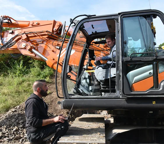 A worker setting up the system on the excavator