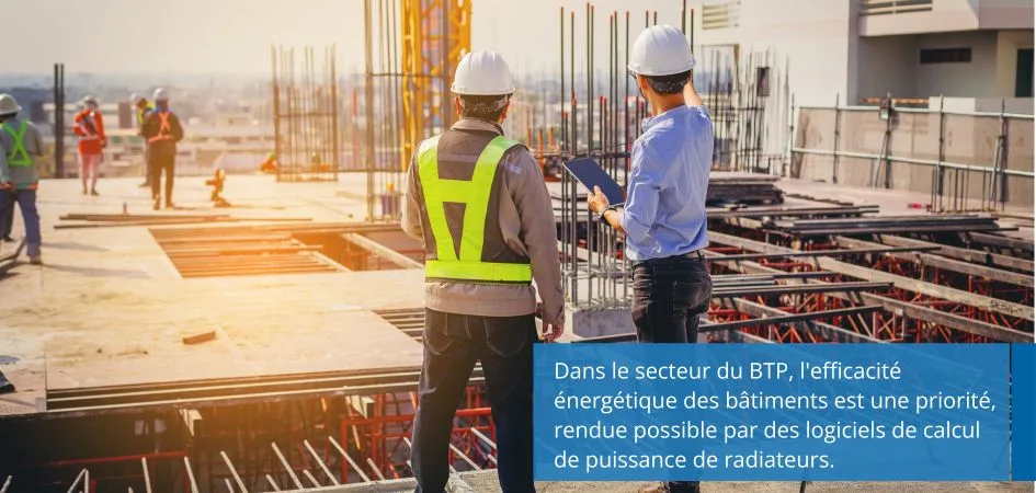 Two construction workers in hard hats and safety vests are looking at a tablet on a building site.