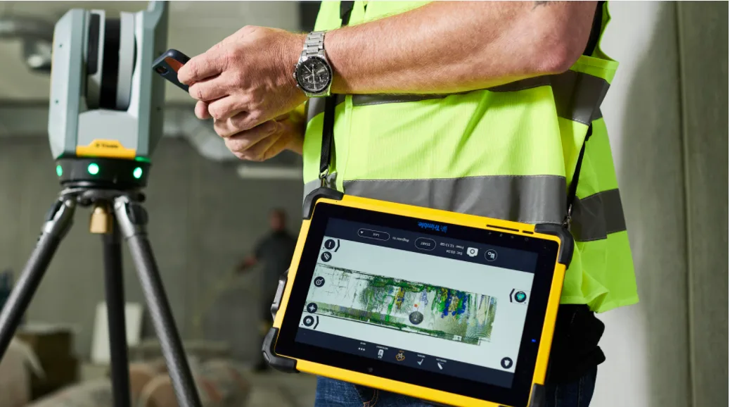 Construction worker uses a 3D scanner and tablet on a job site.
