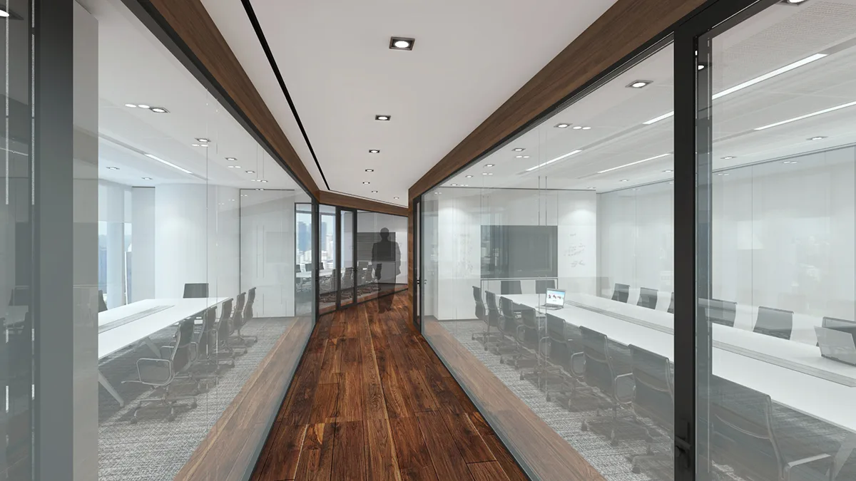 Modern office corridor with glass-walled meeting rooms on either side, featuring long tables and chairs.