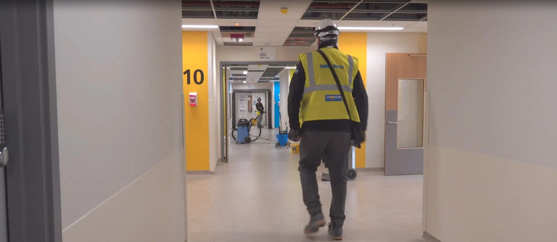 Balfour Beatty worker in safety gear walking through a Midland Metropolitan Hospital hallway under construction.