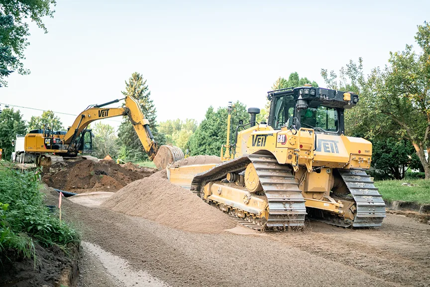 Yellow excavator and bulldozer working on a construction site, moving dirt and gravel.