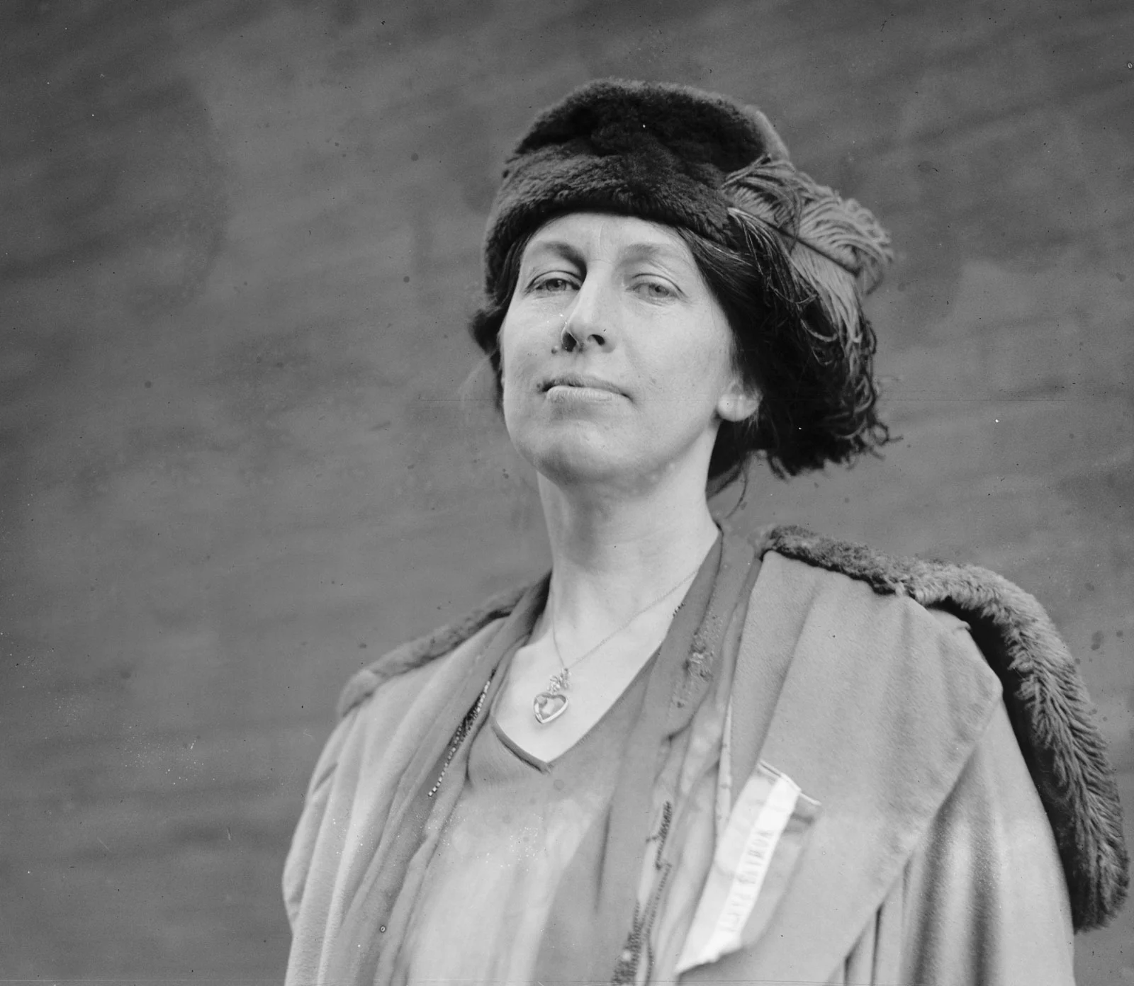 Portrait of a woman wearing a feathered hat and a fur-trimmed coat.