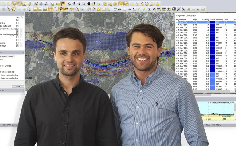 Two smiling men stand in front of a screen displaying GIS mapping software with data tables.