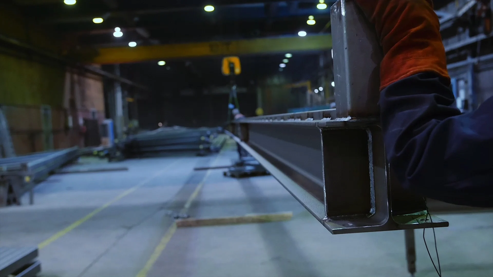 A close-up shot of a steel I-beam being held by a worker in an industrial setting.