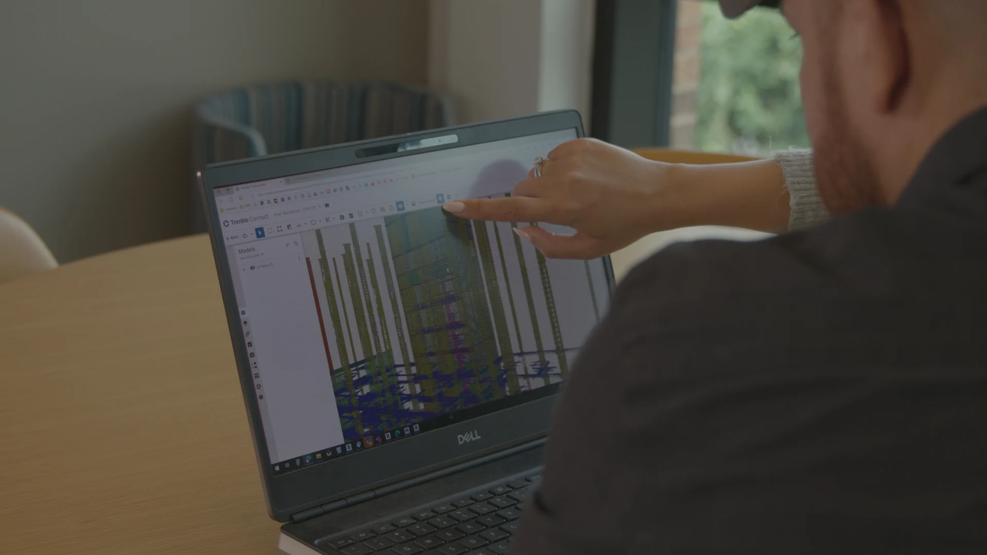 Two people look at a laptop showing a 3D model.