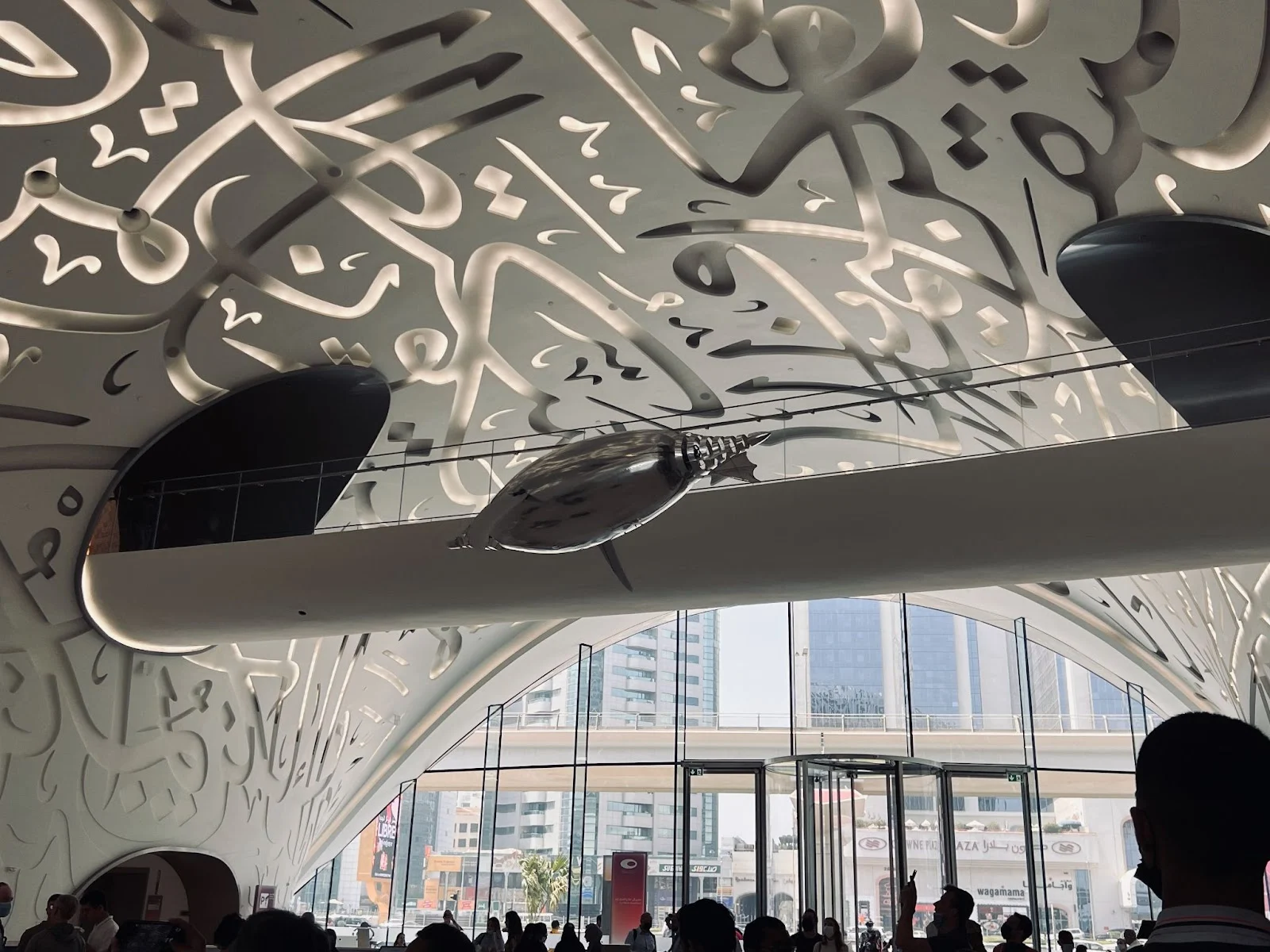Interior view of Dubai Museum of the Future with calligraphy on the ceiling and a suspended exhibit.