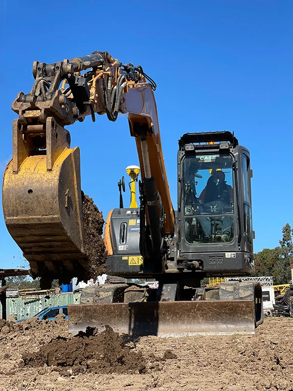 Excavator digging dirt with operator in the cab.