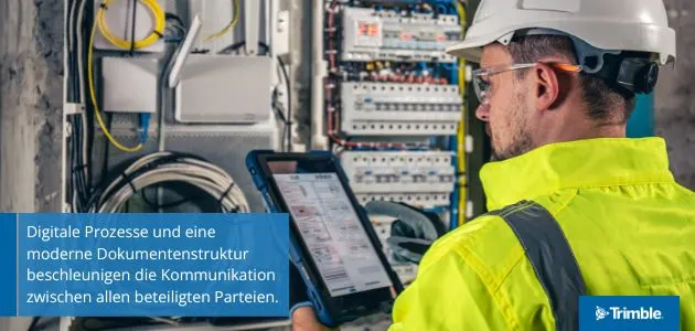 A worker in a hard hat and safety vest uses a tablet in front of an electrical panel.