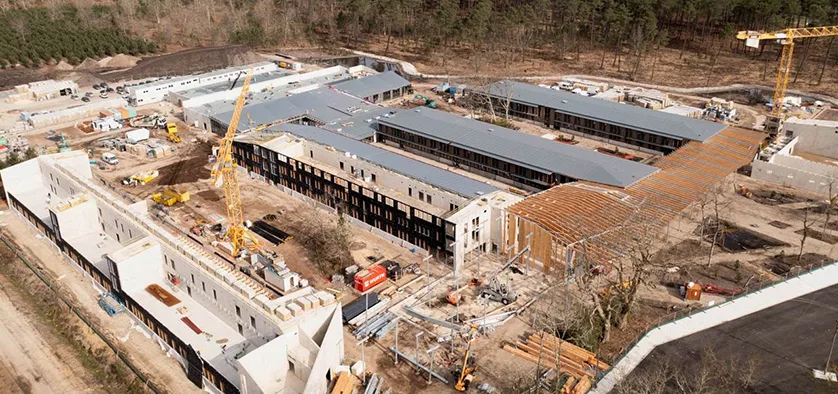 Aerial view of a large construction site with multiple buildings under development, cranes, and construction materials.