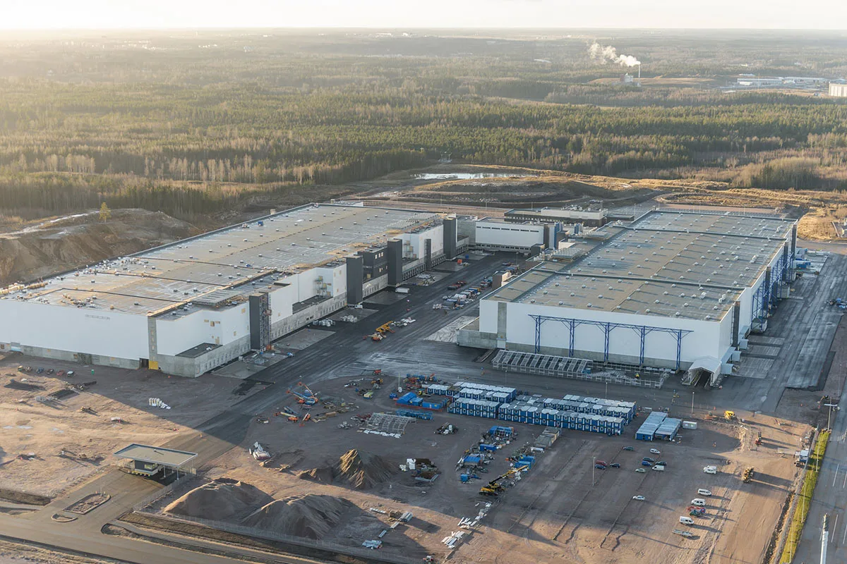 Aerial view of a large, modern industrial complex under construction, with multiple large buildings and surrounding undeveloped land.