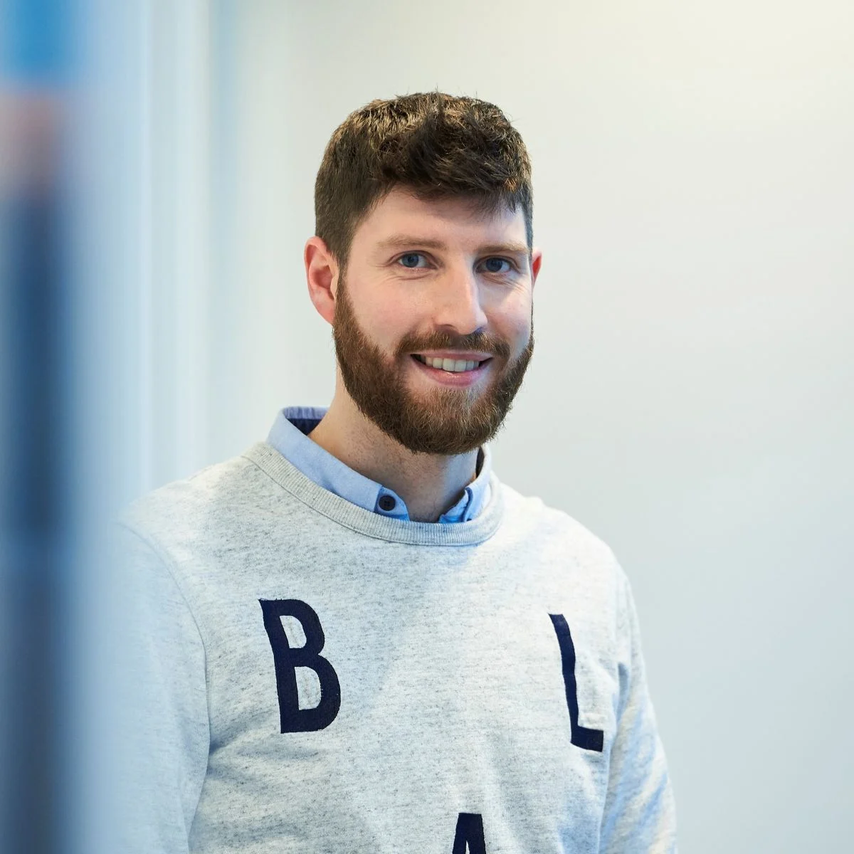Robbe Verfaille smiles warmly, wearing a grey sweatshirt with blue letters across the chest.