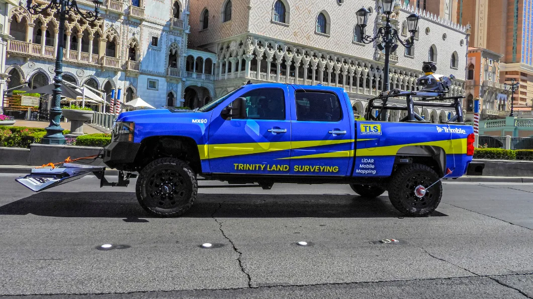 Blue and yellow Trinity Land Surveying truck with LiDAR mobile mapping equipment parked on the Las Vegas Strip.