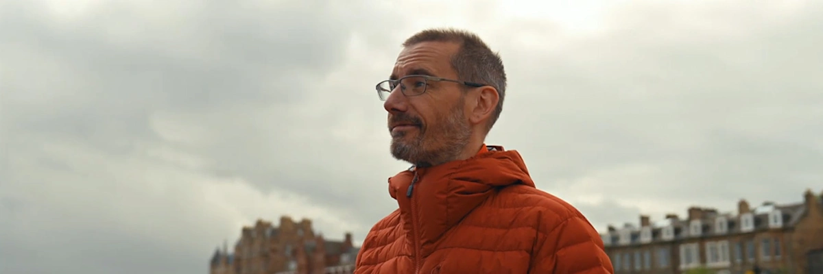 James Lewis of Hive Structural smiling in an orange coat with houses in the background.