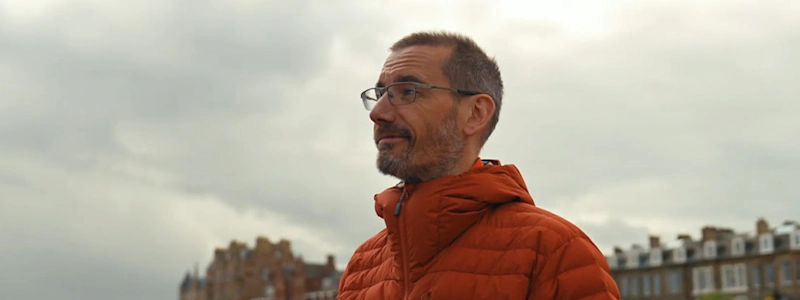 James Lewis of Hive Structural smiling in an orange coat with houses in the background.