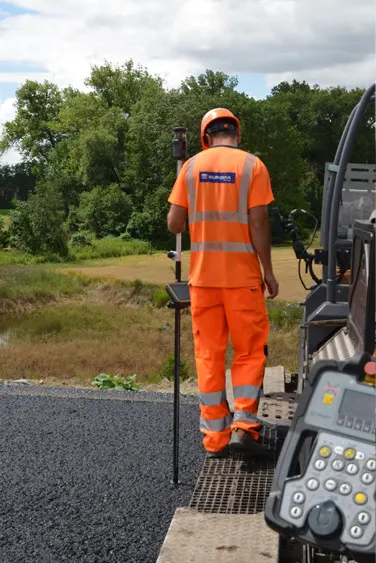 Worker checking height behind paver