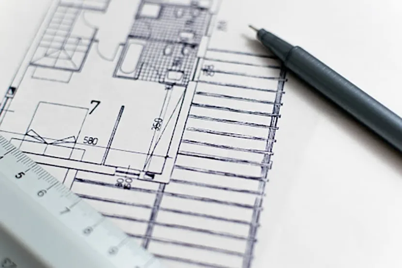 Close-up of a blueprint with a ruler and pen, indicating precision in 3D modeling.