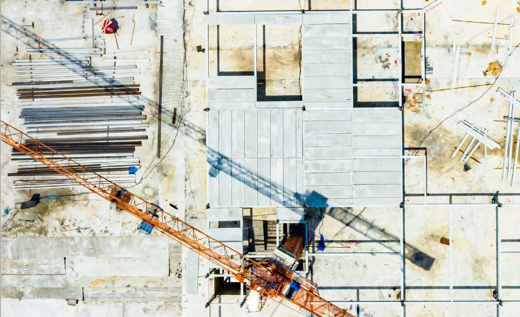 Aerial view of a construction site with a large crane and stacks of building materials.