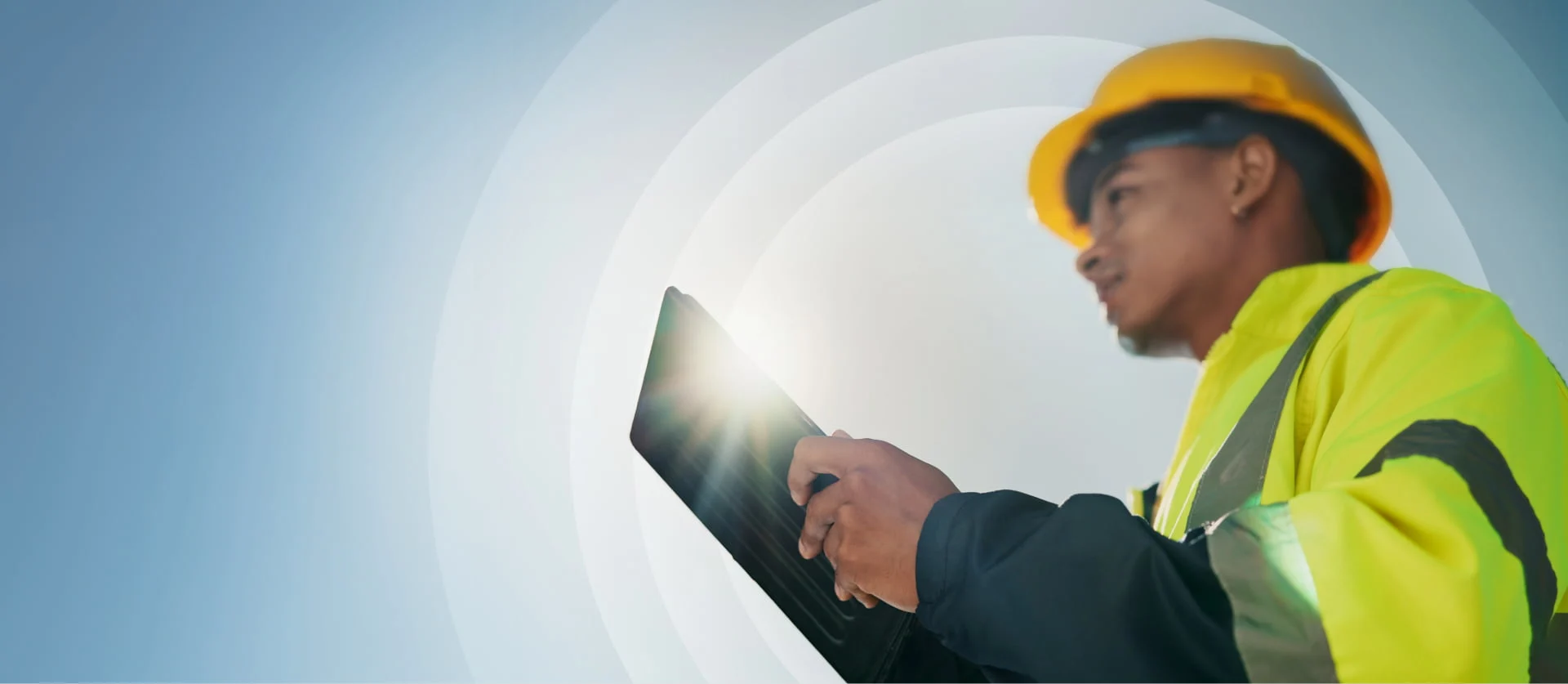 Veldwerker met gele bouwhelm houdt een tablet vast – lensflare.