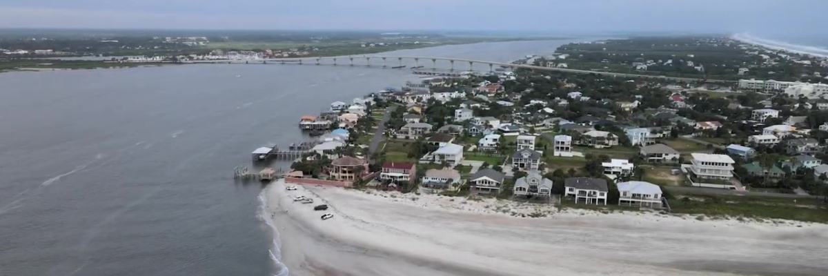 Bridge spans water between the mainland and a strip of land with docks and beachfront houses in St. Johns County, Florida.
