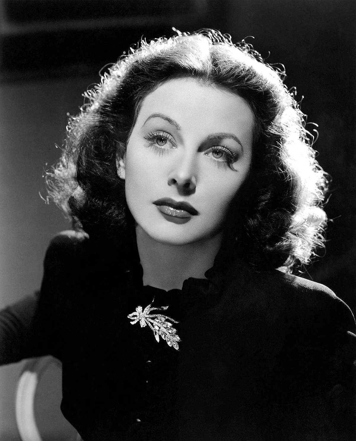 Hedy Lamarr in a black dress with a sparkling brooch, circa 1940s.