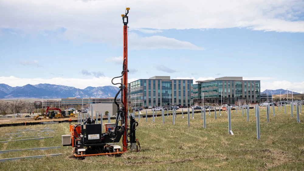 Pile driver installing piles for solar farm