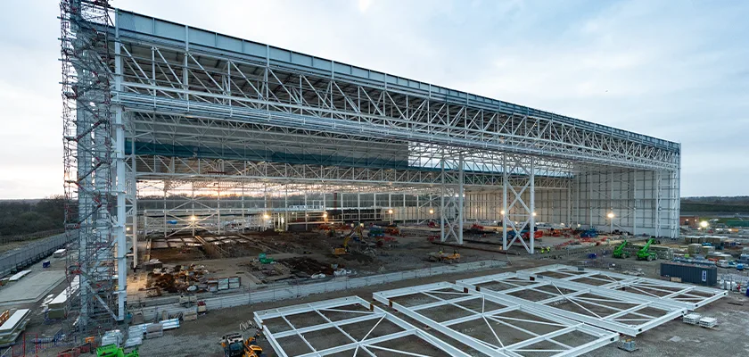 Boeing hanger steelwork with staircase, panels lay on ground ready for assembly in front of hanger