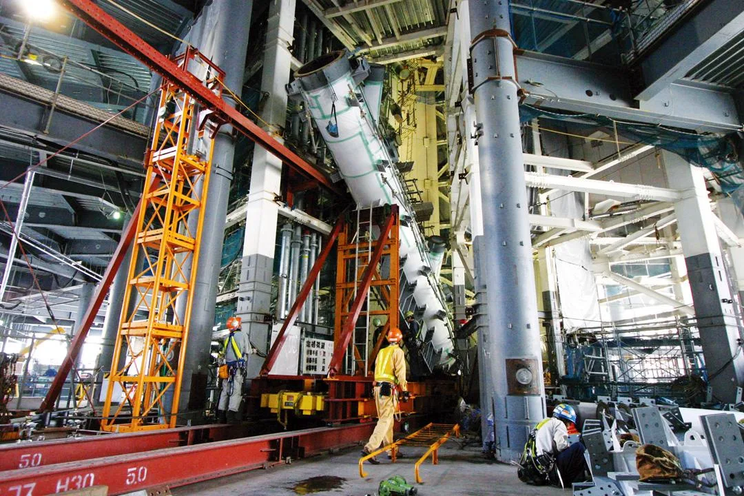 Construction of the Tokyo Skytree: Workers and machinery are seen working on the massive tower structure inside a building.