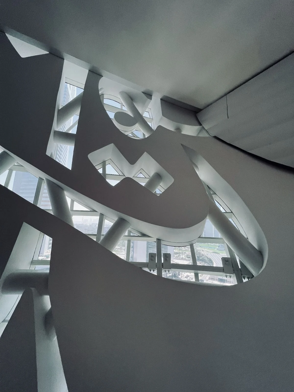 Modern abstract architecture with curved lines and geometric shapes, looking up from below.
