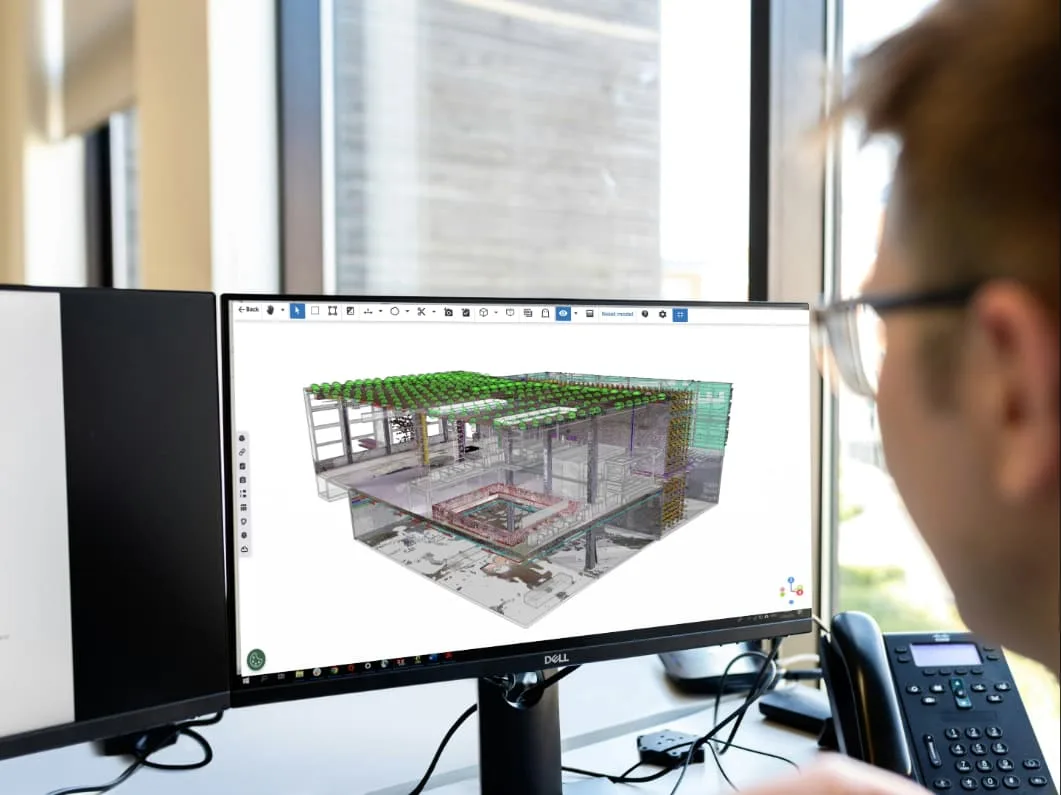 Engineer reviewing a 3D model of a building on a computer screen in an office.