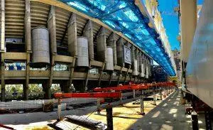 Santiago Bernabéu stadium under renovation, with scaffolding and blue netting covering part of the structure.