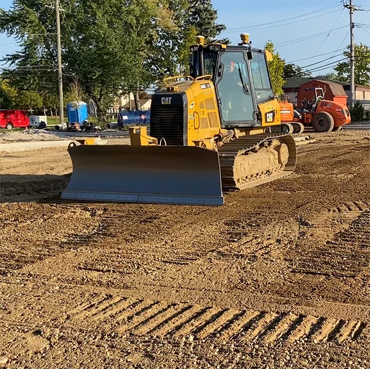 A yellow Caterpillar bulldozer sits on a dirt construction site, ready to grade the land.