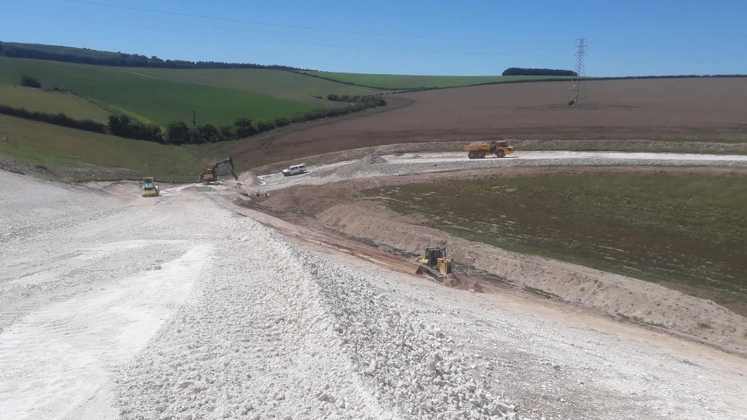 Construction vehicles working on earthworks in a rural landscape
