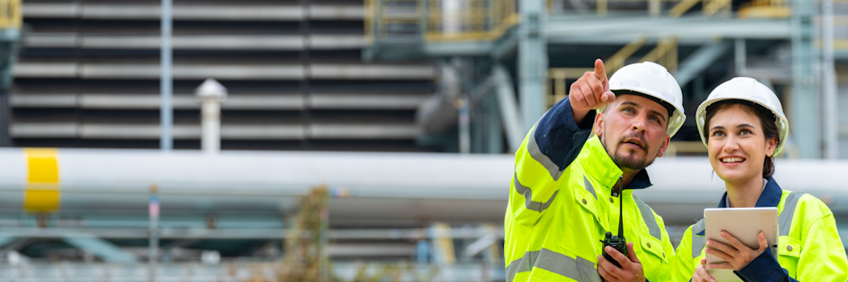 Two workers in safety gear discussing at an industrial site.
