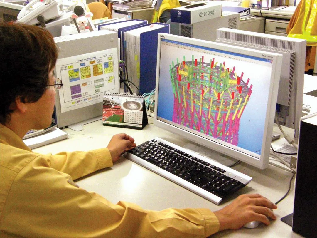 An engineer works on a computer displaying a 3D model of the Tokyo Skytree construction.