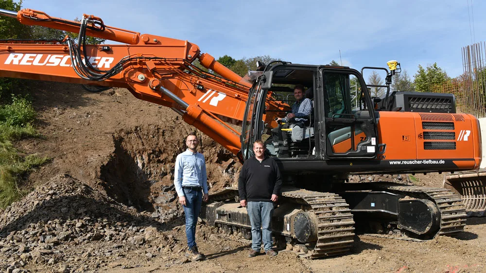 People standing next to a excavator