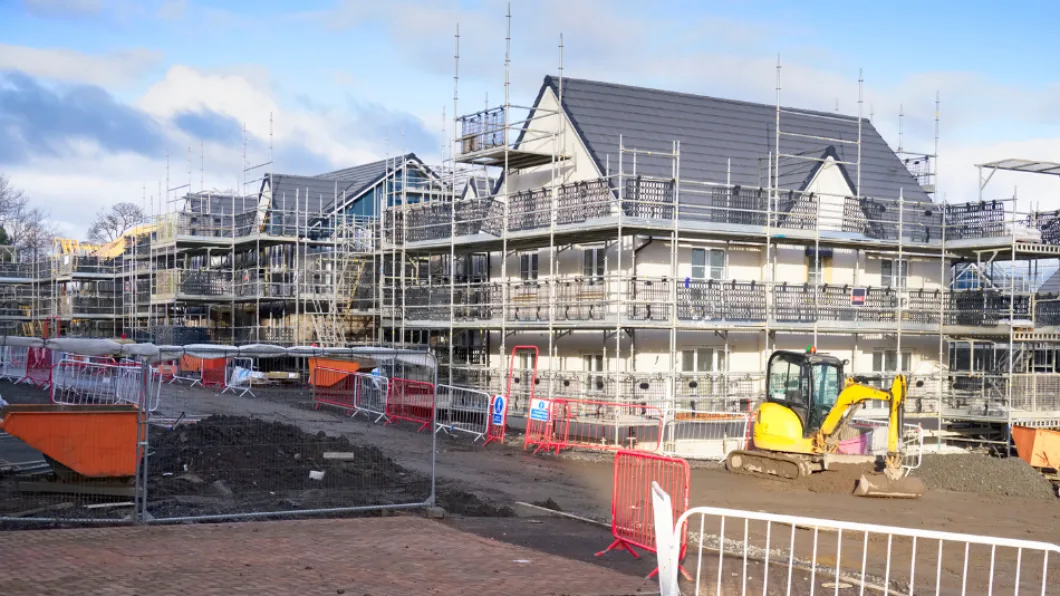 Scaffolding on buildings at a residential construction site with machinery and barriers