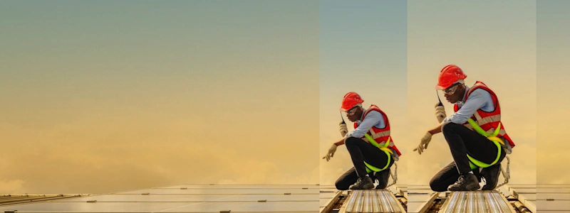 A man holding a radio, wearing a hard hat and orange hi-vis vest, is kneeling on a roof and pointing at solar panels.